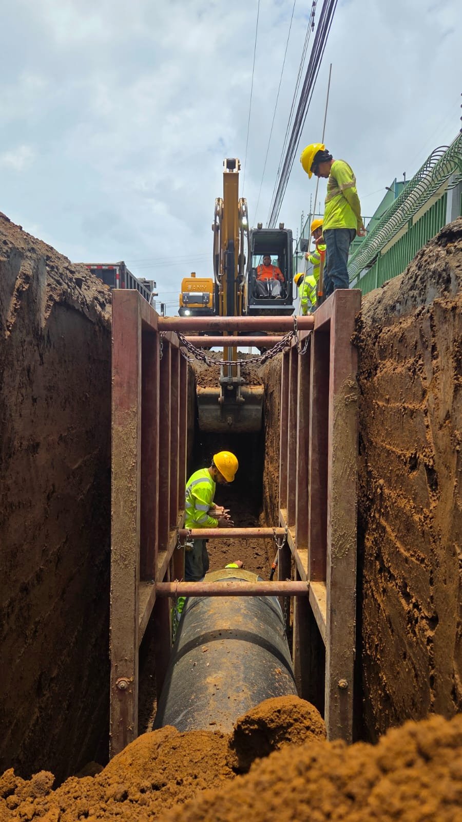 Cuadrilla instalando tubería en una zanja apuntalada